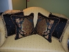 Beautiful black pillows with trim and a mitered frame surrounding the  floral inset.